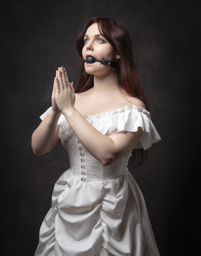 Woman seemingly praying with a gagball in her mouth